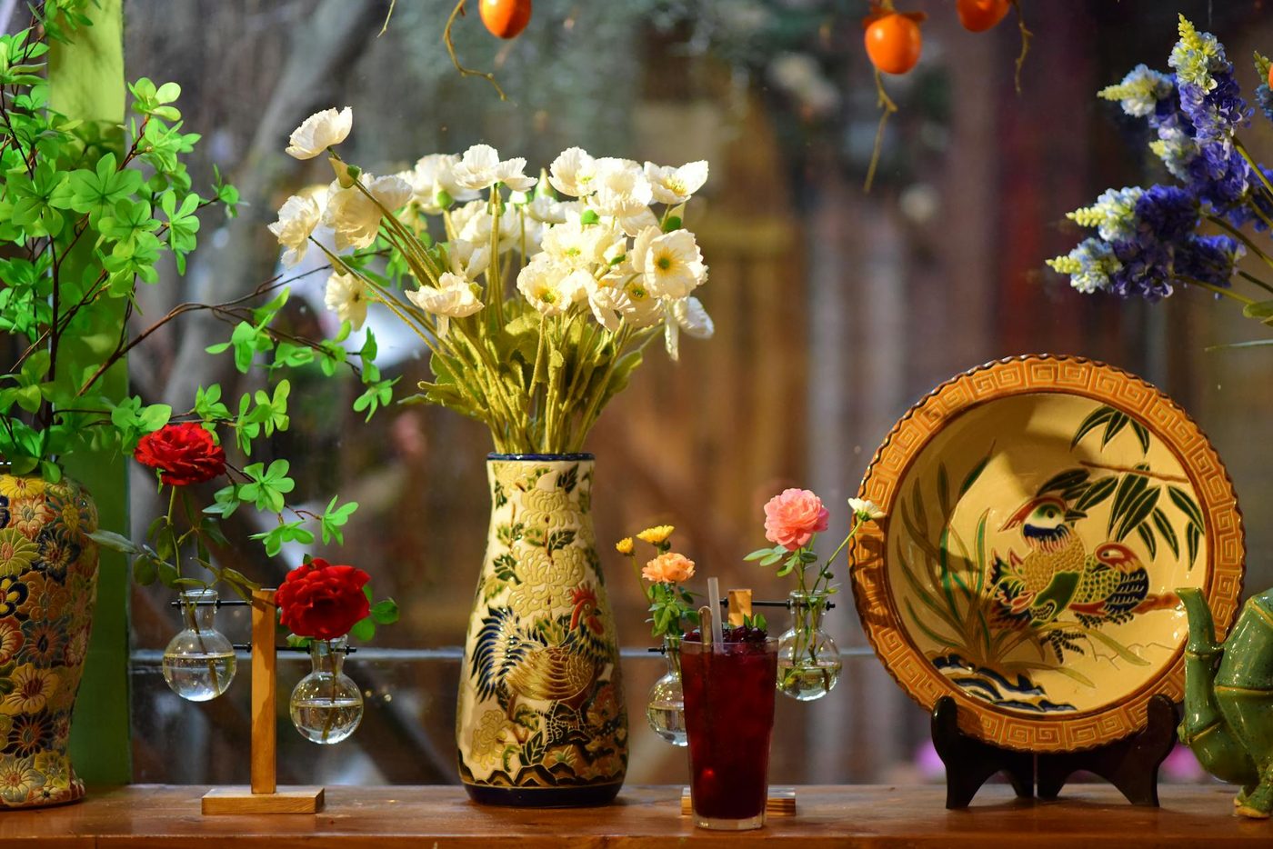 Composition florale de fleurs blanches montée dans un vase peint par l'Atelier Camélia